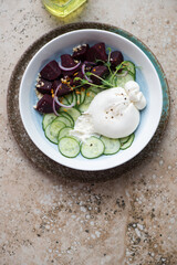 Salad with burrata cheese, cucumber and beets on a beige granite background, vertical shot with space, top view
