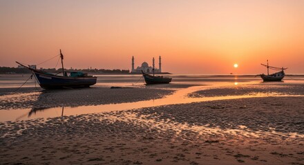 Fototapeta premium Tranquil Sunset Over Beach with Fishing Boats and Mosque in the Background, Soft Colors and Warm Reflections on the Water Surface
