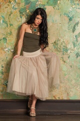 Attractive young fashion woman standing against green stucco wall background