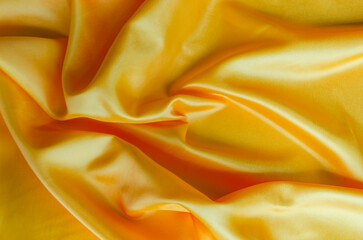 Golden yellow satin textile with shimmering highlights. Suitable for design and wallpaper background