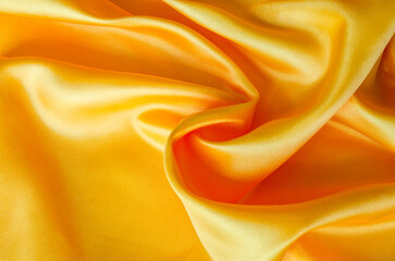 Obraz premium Close up of luxurious golden yellow silk fabric with elegant folds and smooth, glossy surface texture.