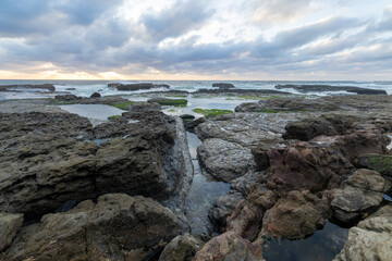 Rocky coastline emerging from the ocean at magoito beach in sintra, portugal