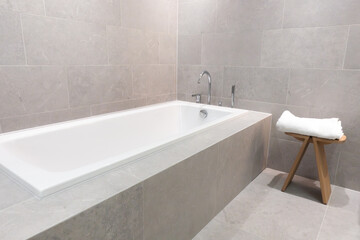 Modern built-in ceramic bathtub with stainless steel and chrome faucets in a contemporary bathroom...