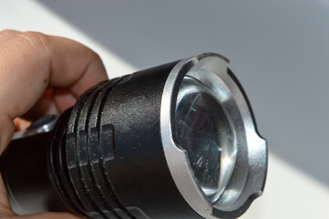 close-up photo of a black tactical flashlight white surface durable textured power button lighting functional design camping hiking survival gear tech gadget power electricity light went out security 