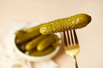 A fork with pickled cucumbers. Homemade pickles in a jar on a light background.