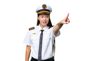 Airplane pilot Asian woman over isolated background pointing away