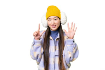 Young Asian woman wearing winter muffs over isolated chroma key background counting seven with fingers