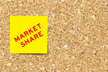 Yellow note paper with word market share on cork board background with copy space