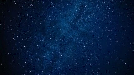 Wide-angle view of the night sky filled with stars and the glowing Milky Way galaxy in deep blue tones, featuring cosmic depth and celestial beauty in sharp high-resolution landscape format.