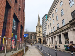 A city street with St John's Church flanked by modern and historic buildings