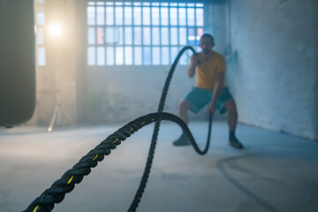 A man is deeply engaged in an intense battle rope workout, showcasing his determination in an urban...