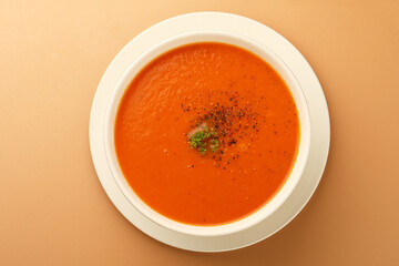 bowl of tomato soup with parsley on brown background