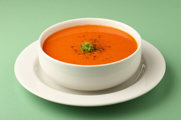 bowl of tomato soup with parsley on green background