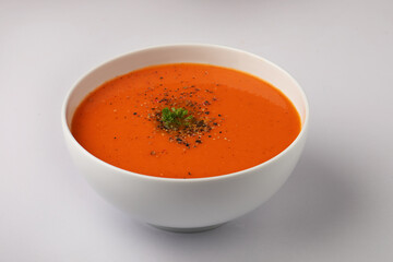 bowl of tomato soup with parsley on white background