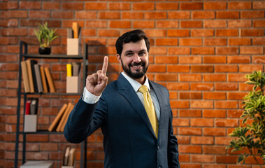Corporate Indian man counting digits with fingers while standing in office against brick wall