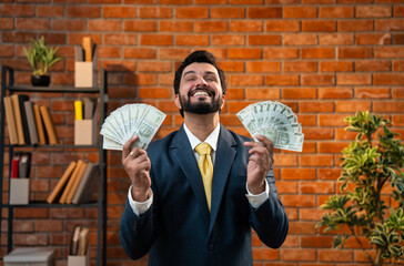 Asian CEO holding rupee money fan in stylish office, flaunting profit or success proudly