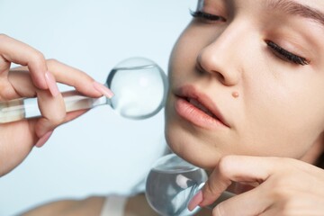 Elegant woman examining skin using magnifying glass in bright setting