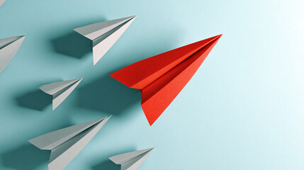 Fototapeta premium Red paper airplane leading a group of gray ones on a light-blue background, symbolizing leadership, innovation, and standing out from the crowd. Free space for text