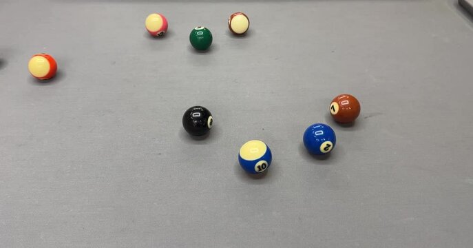 Hand preparing to shoot with a cue stick on a gray pool table, aiming at the cue ball with several balls scattered around. Focus on precision, strategy, and billiard gameplay.