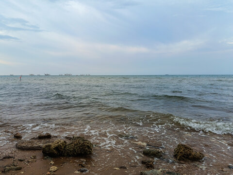 Tranquil Rocky Seaside with Overcast Sky and Gentle Waves