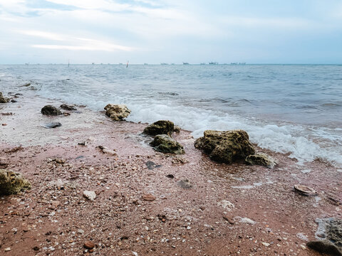 Tranquil Rocky Seaside with Overcast Sky and Gentle Waves