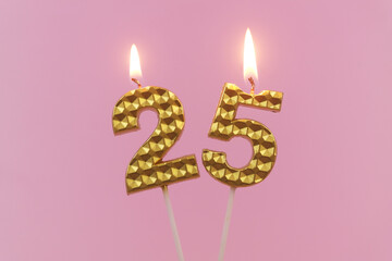 Burning golden birthday candles on pink background, number 25	