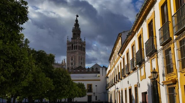 Giralda, the bell tower of Seville Cathedral, rising majestically over the cityscape under a dramatic cloudy sky in Seville, Spain