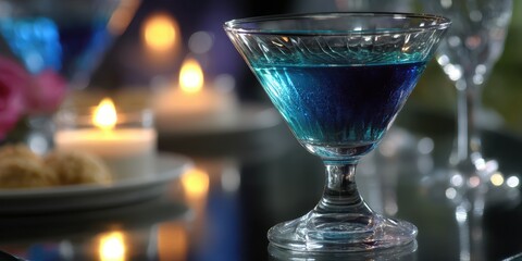 Blue cocktail served on a table with candles and snacks at a cozy evening gathering