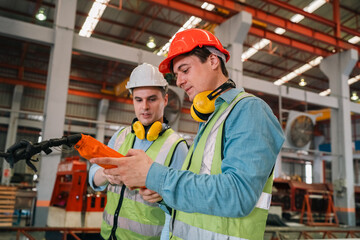 Industrial technicians collaborate in factory, focusing production systems, equipment operation,...