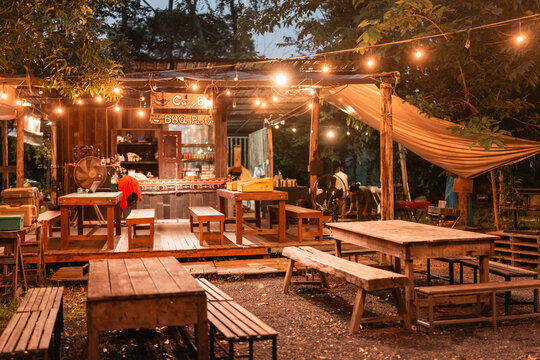 cozy outdoor dining area set up for a rustic BBQ party offering relaxed camp style atmosphere where friends, families gather to enjoy grilled food and create unforgettable memories under the lights