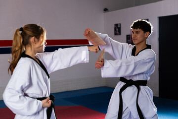 Determined female taekwondo fighter breaking wooden board during training