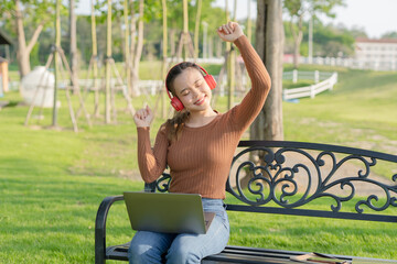 Asian woman using headphones to dance
Outdoors, park