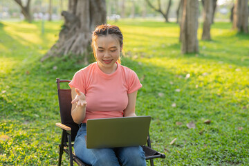 Asian woman sitting working under a tree outdoors in the evening light.