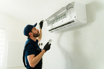 Male technician installing or repairing air conditioning unit