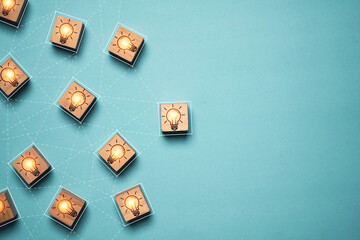 Glowing light bulb linkage on wooden block cube with copy space for brainstorming to creative...