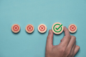Hand holding green correct sign mark among Red Cross mark for business project approval and document approve concept.