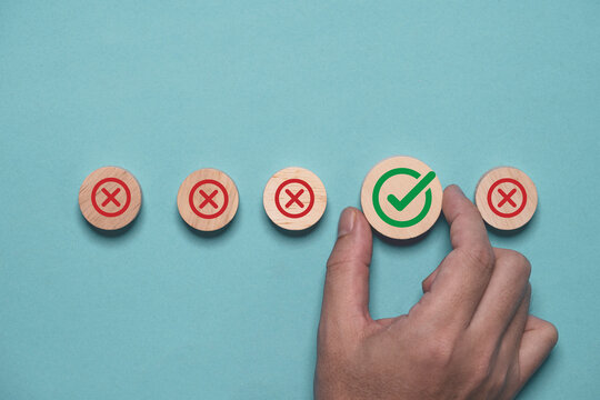 Hand holding green correct sign mark among Red Cross mark for business project approval and document approve concept.