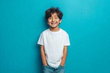 Happy smilling boy wearing bella canvas white shirt mockup, at blue background. Design tshirt template, print presentation mock-up