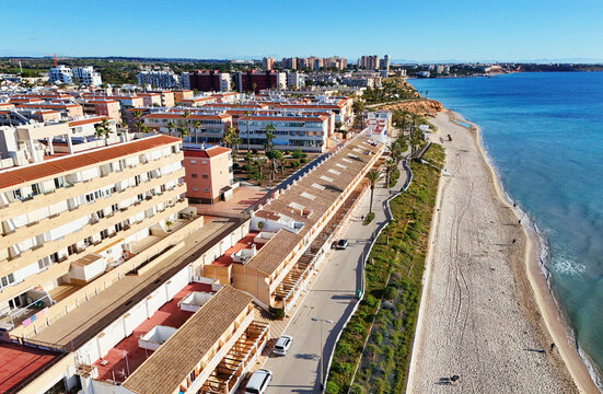 Aerial view Mil Palmeras coastline, showing beachfront houses, promenade, sandy beach and turquoise Mediterranean Sea under clear blue sky, ideal for travel, tourism, real estate. Costa Blanca, Spain - Powered by Adobe