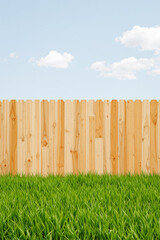 Fototapeta premium lush green grass and wooden fence under a partly cloudy sky