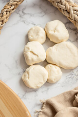 five smooth dough balls ready for baking on marble surface