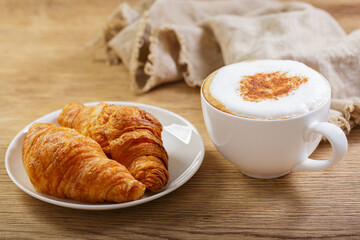 Cup of cappuccino coffee with croissants