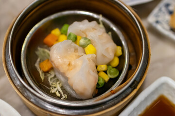 Delicious dim sum served in a bamboo steamer with colorful vegetable mix.