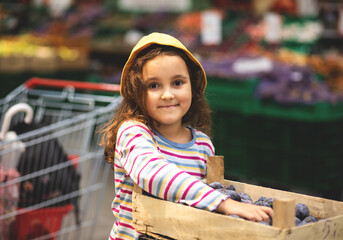 Kid little cute girl shopping for fresh organic fruits and vegetables in supermarket