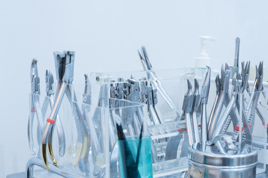 Different dental tools for demonstration patient.Dental mirror, sickle probe and surgical forceps on blue background.Dentist healthcare education concept.