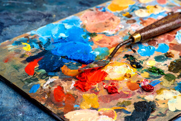 Old used palette knife, palette with multi-colored spots of oil or acrylic paint in an artist's...