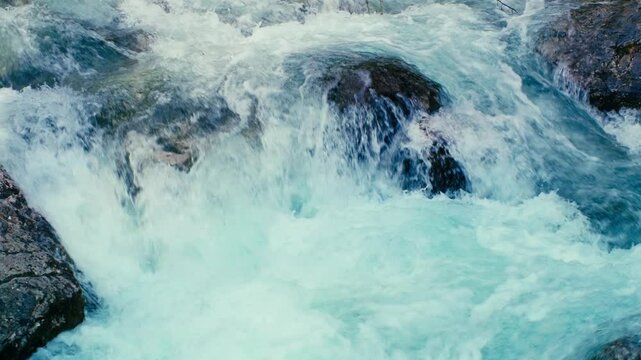 Fast-flowing river rushing through a rocky canyon, with powerful water currents navigating around large boulders. Natural energy and dynamic movement captured in a scenic wilderness setting