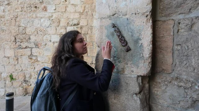 Young tourist woman touching a Mezuza in Jerusalem, in Zion Gate. 