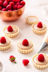 six raspberry caramel tarts artfully arranged on a white background