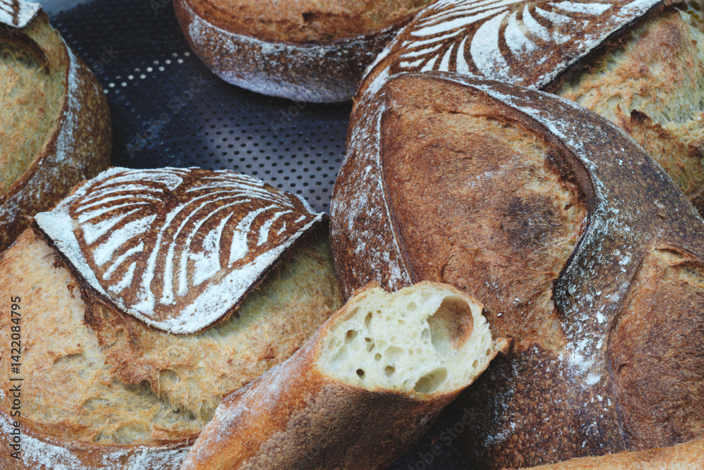 Poster A display of bread with a variety of shapes and sizes. The bread is arranged on shelves and is ready to be sold.